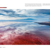 Experience the vivid beauty of Lake Natron, as captured in "The Colors of the Earth" by Schiffer Publishing, Ltd.—red waters, dramatic skies, and reflections of clouds and mountains create a stunning Tanzanian panorama.