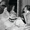 A woman in a nightgown sits on a bed as a man talks on the phone—a scene echoing The Art of Classic Crime and Mystery Movies by Schiffer Publishing, Ltd., with a mirror, drapes, and wallpaper creating a cinematic backdrop.