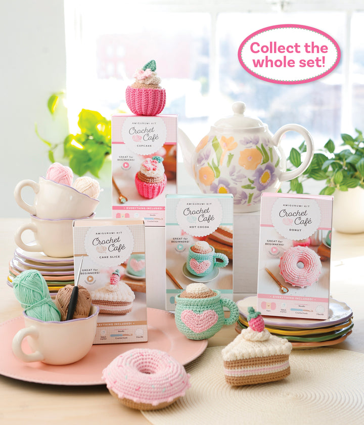 A vibrant array of Schiffer Publishing, Ltd.'s Crochet Cafe Amigurumi Kit Cupcake is styled with yarn on pastel plates. A floral teapot and teacup set decorate the background. Text: Collect the whole set!.