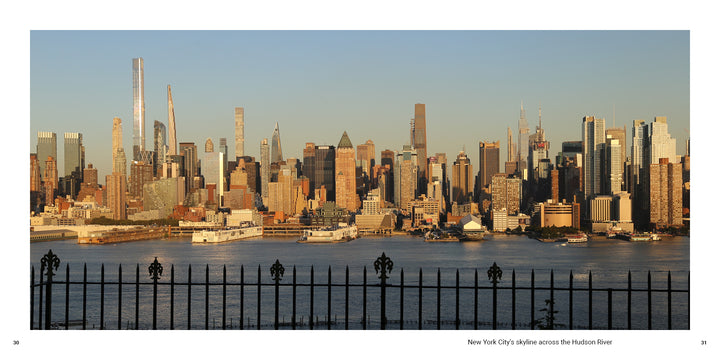 The New York City skyline viewed across the Hudson River behind a decorative iron fence, reminiscent of a souvenir photo book.