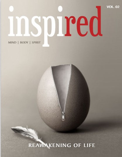 An egg with a zipper partially open stands upright next to a feather on a gray surface. The magazine cover reads Inspired with red in red letters, and the headline Reawakening of Life.