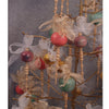 A decorative display for "Wood Turning, from Tree to Table" by Schiffer Publishing, Ltd. features spindles and colorful ornaments with gold and white ribbon bows on a gold stand, set against a gray background.