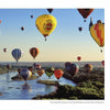 Experience the magic of the Albuquerque International Balloon Fiesta with "Balloons Over Albuquerque" by Schiffer Publishing, Ltd., featuring vibrant hot-air balloons soaring above a scenic river and lush landscape under clear blue skies.