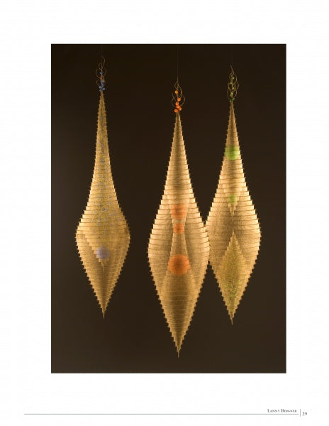 Three elongated, symmetrical fiber sculptures with translucent golden layers and colorful accents are featured as striking textile art in "Fiber Art Today" by Schiffer Publishing, Ltd.