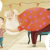 An illustration from "The Magic in a Smile" by Schiffer Publishing, Ltd. shows an elderly person in a pink polka-dot dress bending to talk to a smiling child, as speech bubbles about emotions appear in their cozy, warmly lit room.