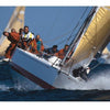 A group sails a racing yacht with yellow sails, leaning over the edge as it cuts through the water in this striking photo from "Sailing Fascination" by Schiffer Publishing, Ltd. Other boats are seen in the background on a sunny day.