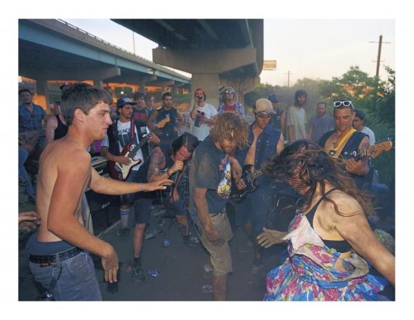 A lively crowd gathers under a highway near the D-I-Y skate spot, playing guitars and dancing—a scene captured in "FDR Skatepark: A Visual History" by Schiffer Publishing, Ltd., celebrating the park’s vibrant skateboarding community.