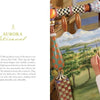 A woman hand-paints a wooden piece next to a vibrant mural. The left page shares how "Celebrating MacKenzie-Childs" from Schiffer Publishing, Ltd. captures the handcrafted style of MacKenzie-Childs decor.