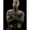A bald, tattooed man with a goatee sits shirtless against a black background, showcasing intricate body art in this powerful image from "The Tattoo Project" by Schiffer Publishing, Ltd.