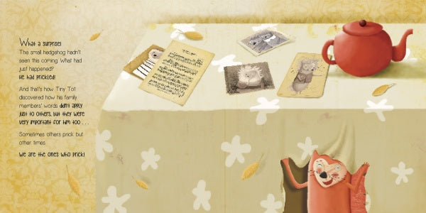A table with a red teapot and three cards sits on a floral cloth. An illustrated orange cat smiles in the corner. "The Hedgehog Who Didn't Want to Prickle" by Schiffer Publishing, Ltd. has text on a patterned yellow background, perfect for kids' emotional intelligence stories.