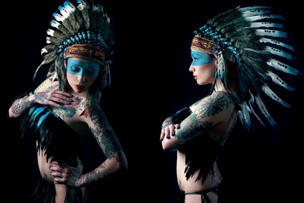 A tattooed woman in a large feathered headdress and blue face paint poses against a dark backdrop, capturing alternative pin-up style in front and side views from "Queens of Hearts" by Schiffer Publishing, Ltd.