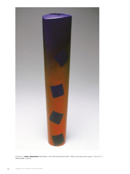 “Turning to Art in Wood” by Schiffer Publishing, Ltd. is a tall, cylindrical sculpture featuring a purple-to-orange gradient and four evenly spaced dark blue squares in a vertical line, shown upright against a plain white background.